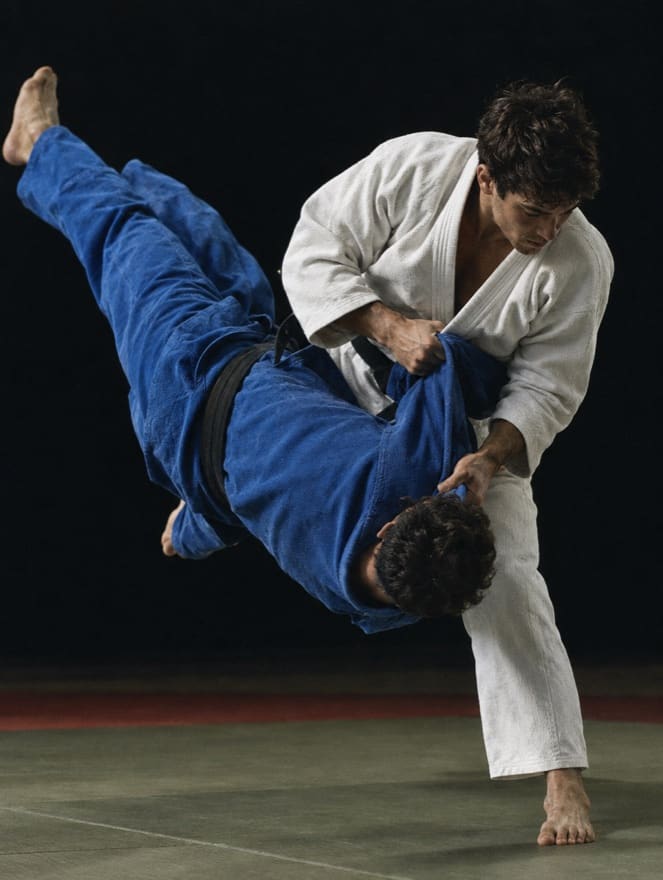 A judoka in a white gi throws a partner in blue